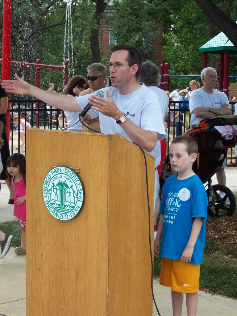 Guest speaker with son speaking and pointing hand at Jonquil Park